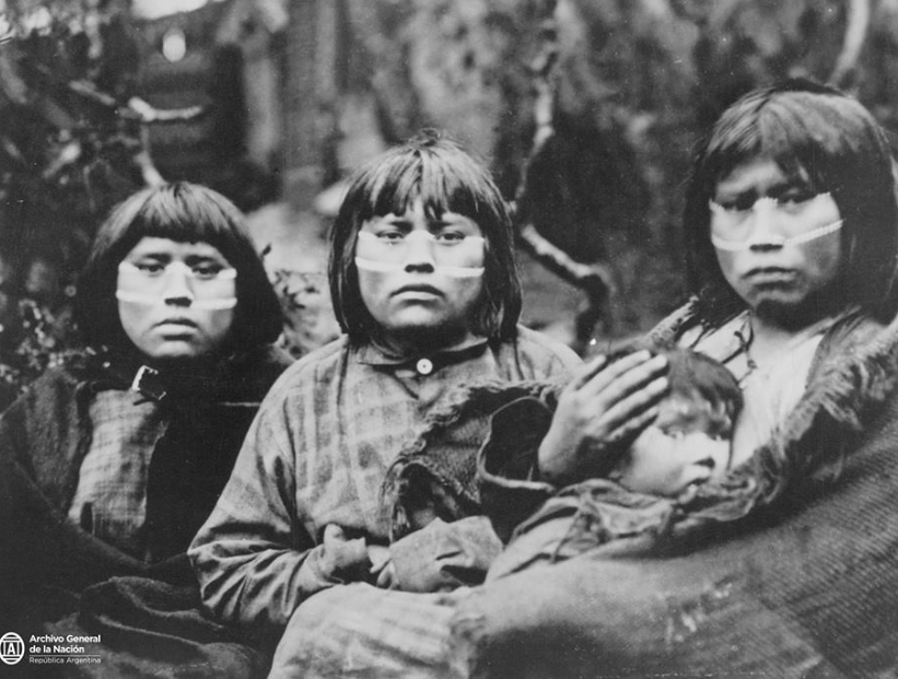 tres mujeres yaganes yamanas en blanco y negro con un bebé en brazos